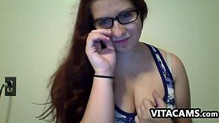 a cute girl with glasses performs solo on webcam at home.