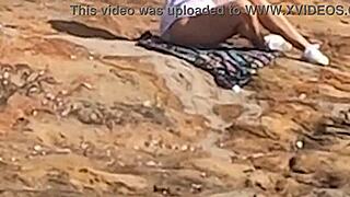 Young beauty watched having public sex on beach rocks