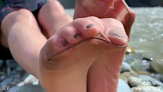 Goddess teases with tan nylons and cute soles by the river